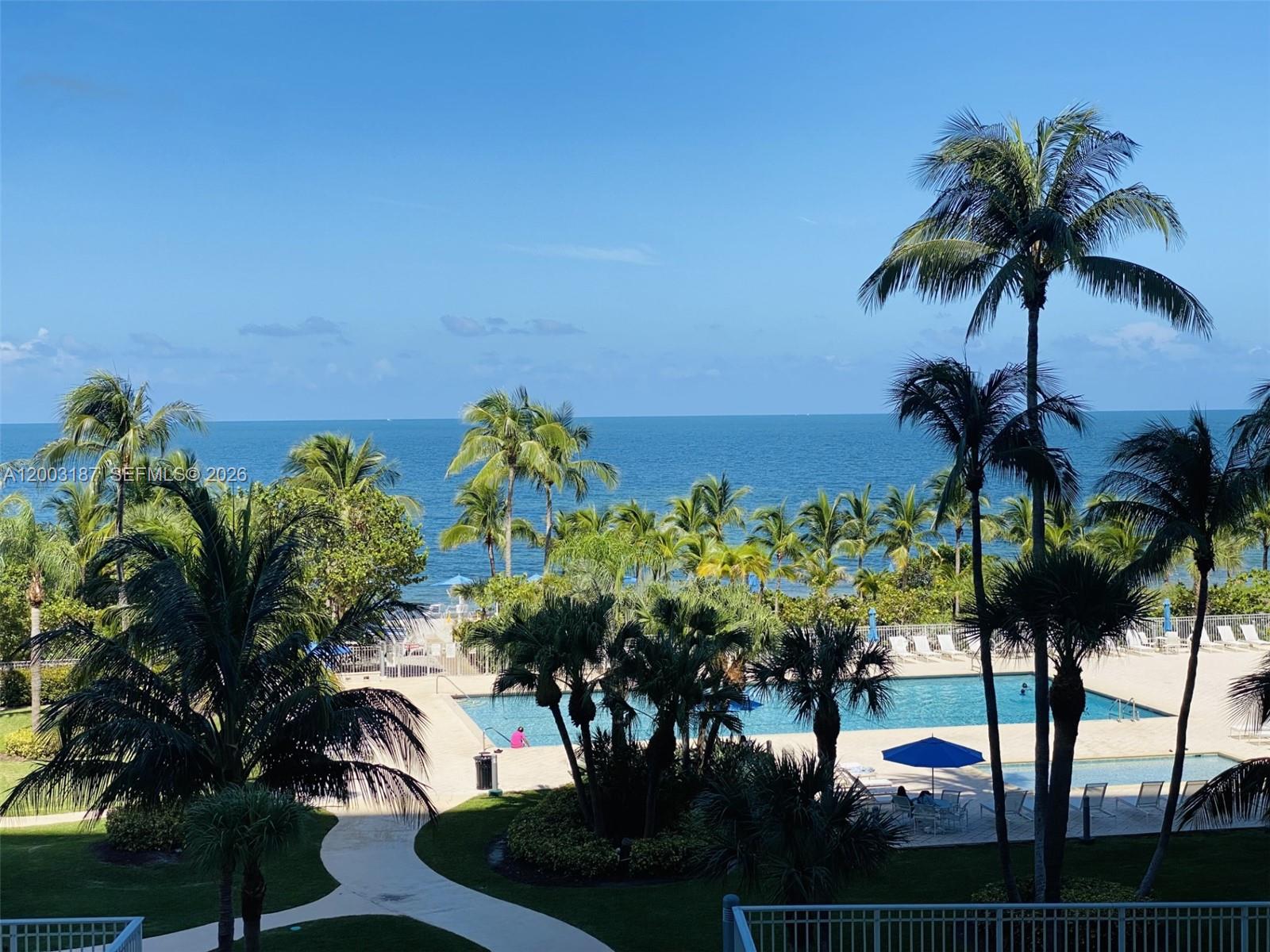 A view of a swimming pool and palm trees overlooking the ocean — 881 Ocean Dr # 3E, Key Biscayne FL 33149, KEY BISCAYNE, FL
