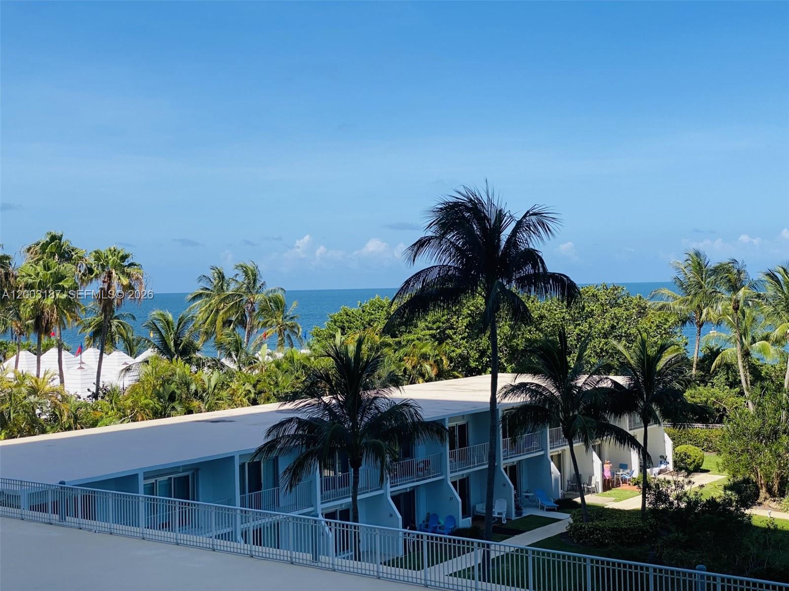 An elevated view shows a blue two-story building with balconies surrounded by palm trees — 881 Ocean Dr # 3E, Key Biscayne FL 33149, KEY BISCAYNE, FL