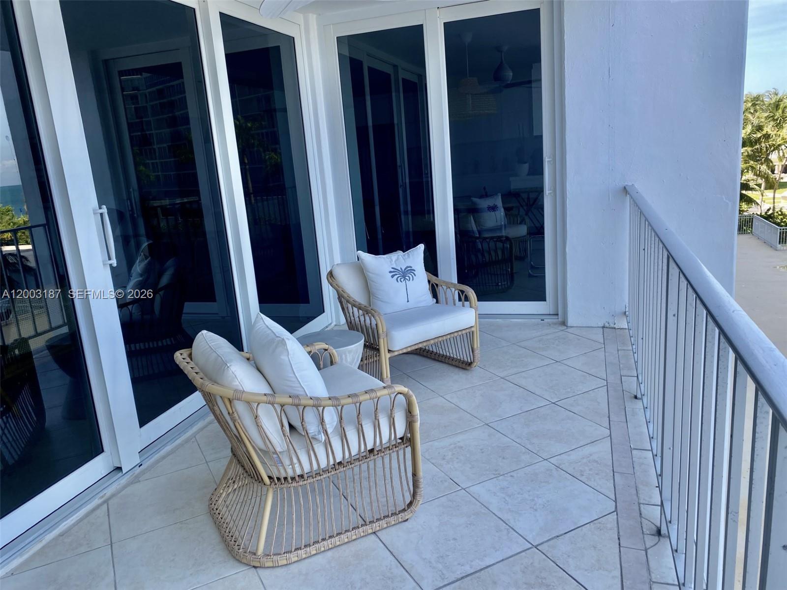 A balcony features two wicker chairs with white cushions and a small side table — 881 Ocean Dr # 3E, Key Biscayne FL 33149, KEY BISCAYNE, FL