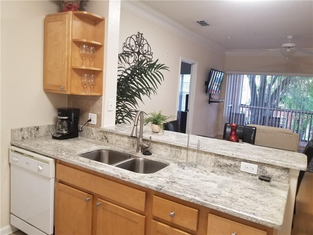 A kitchen features light wood cabinets, granite countertops, a double sink, and a dishwasher — 4207 S DALE MABRY HIGHWAY UNIT 10207, TAMPA, FL