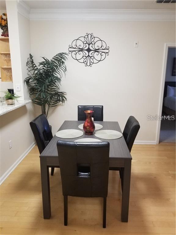 A dining area features a dark wood table with four chairs and wall-mounted metal decor — 4207 S DALE MABRY HIGHWAY UNIT 10207, TAMPA, FL