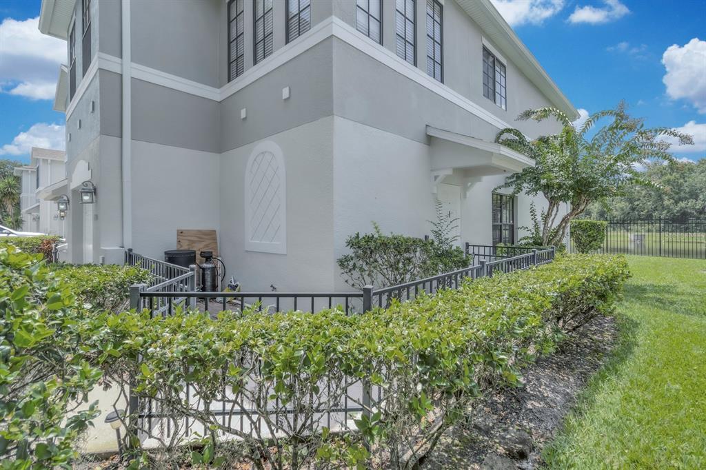 A side view of a two-story gray townhouse with a fenced patio and landscaping — 4210 WINDSOR LAKE CIRCLE, SANFORD, FL