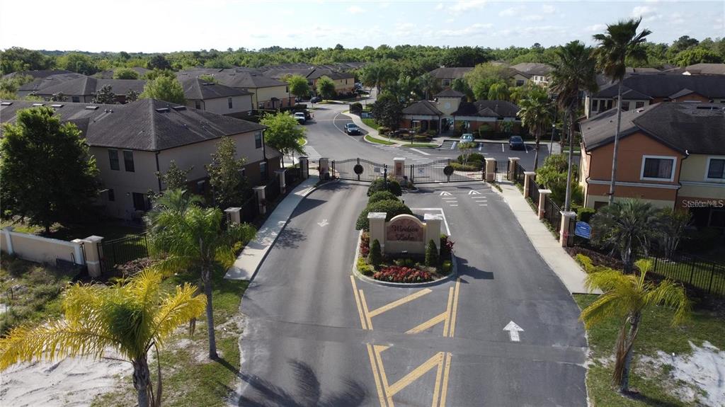 An aerial view of a gated residential community entrance with a central landscaped sign — 4210 WINDSOR LAKE CIRCLE, SANFORD, FL