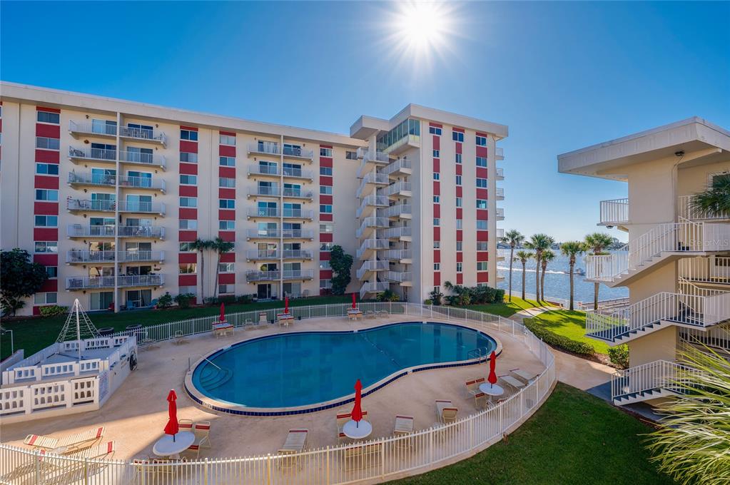 An outdoor swimming pool sits in front of a multi-story apartment building near the water — 2711 N HALIFAX AVENUE UNIT 370, DAYTONA BEACH, FL