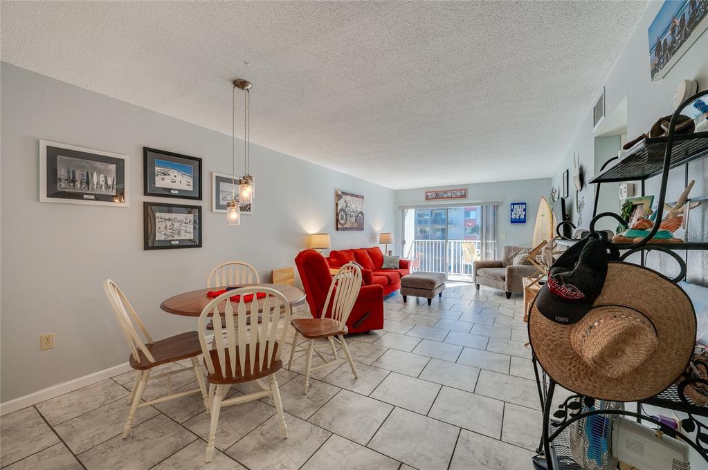 A living and dining area features tile floors, a red sofa, and a round table — 2711 N HALIFAX AVENUE UNIT 370, DAYTONA BEACH, FL