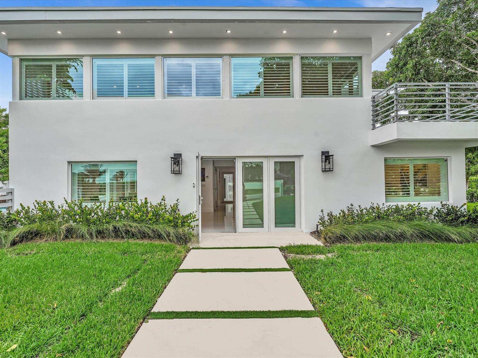 A white two-story house features a concrete walkway leading to a glass-paned front entrance — 1903 Bay Drive, Pompano Beach FL 33062, POMPANO BEACH, FL