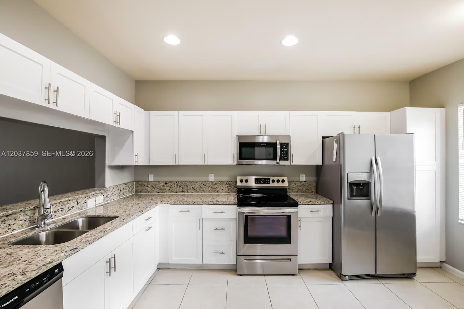 A kitchen features white cabinets, stainless steel appliances, and granite countertops — MIRAMAR, FL