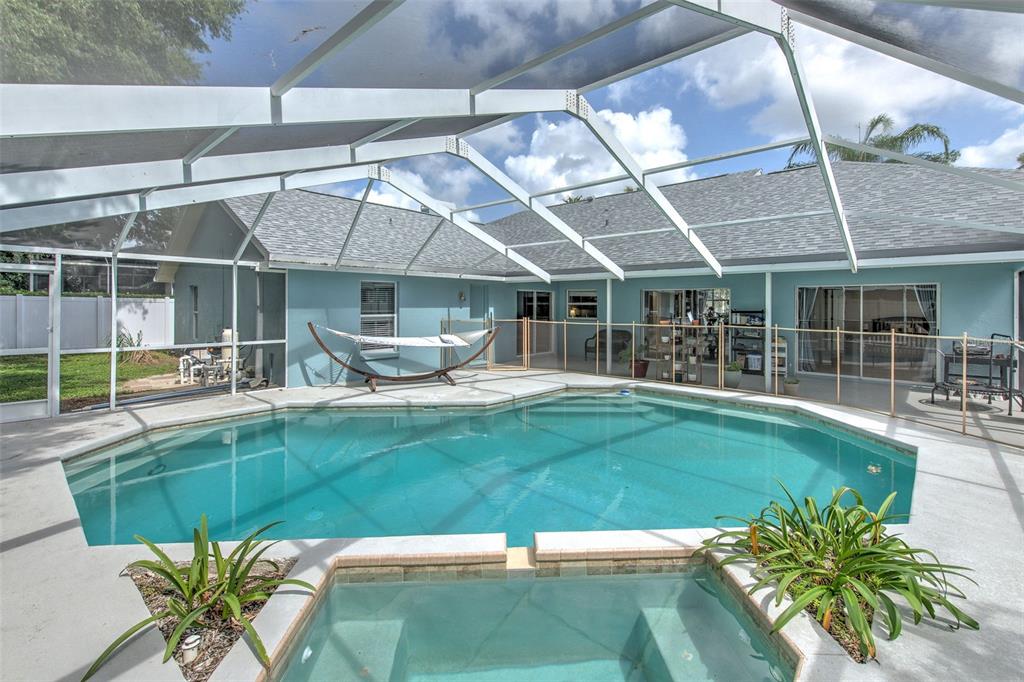 A screened-in patio features a swimming pool, a hot tub, and a hammock — 2327 EAGLE BLUFF DRIVE, VALRICO, FL