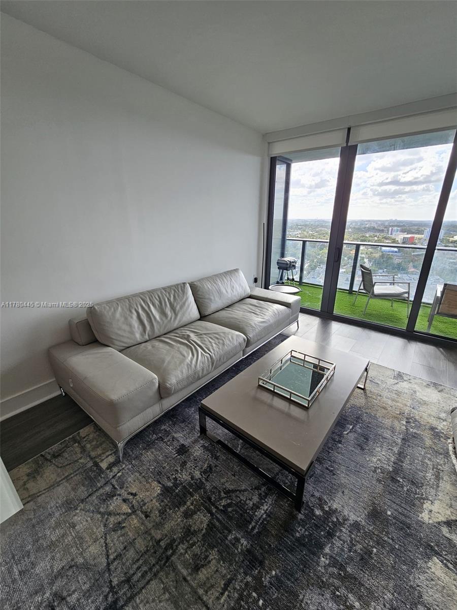 A living room features a light gray sofa, a coffee table, and a balcony view — 121 NE 34 ST # 2511, Miami FL 33137, MIAMI, FL