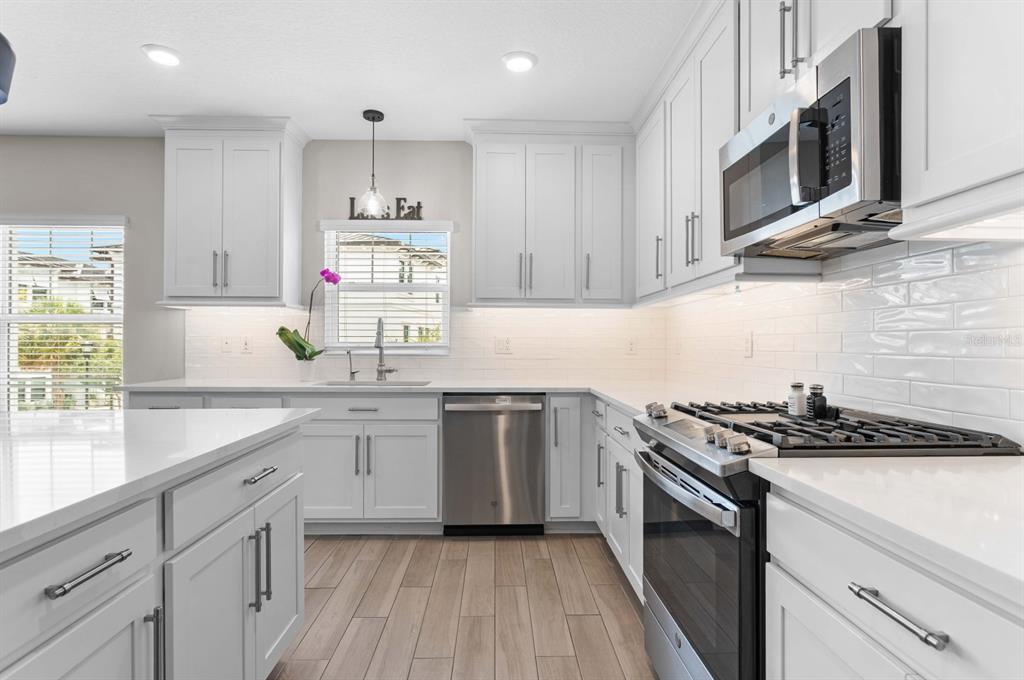 A modern kitchen features white cabinetry, stainless steel appliances, a gas range, and an island — 5351 BRIDGE STREET UNIT 42, TAMPA, FL