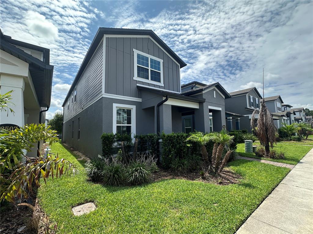 A two-story gray house with white trim and a front lawn under a cloudy sky — 12513 ENCORE AT OVATION WAY, WINTER GARDEN, FL