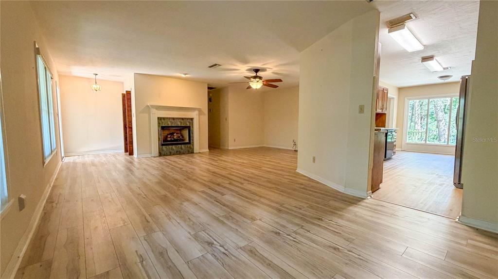 An open-concept living area features light wood-look flooring, a fireplace, and an adjacent kitchen — 11440 SW ARCHER ROAD, GAINESVILLE, FL
