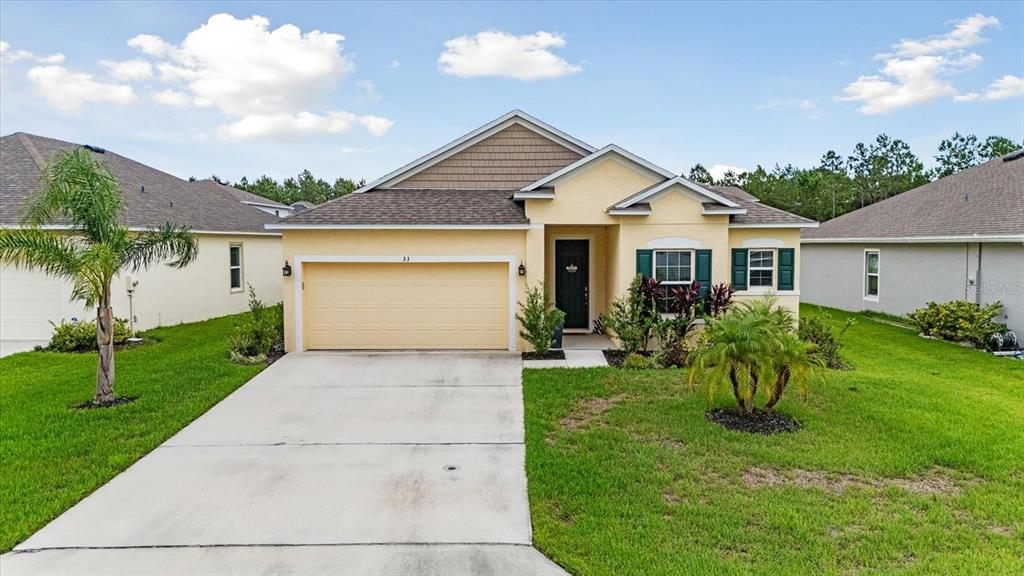 A single-story yellow house with a two-car garage, a concrete driveway, and green shutters — 33 RIDGE ROAD, PALM COAST, FL
