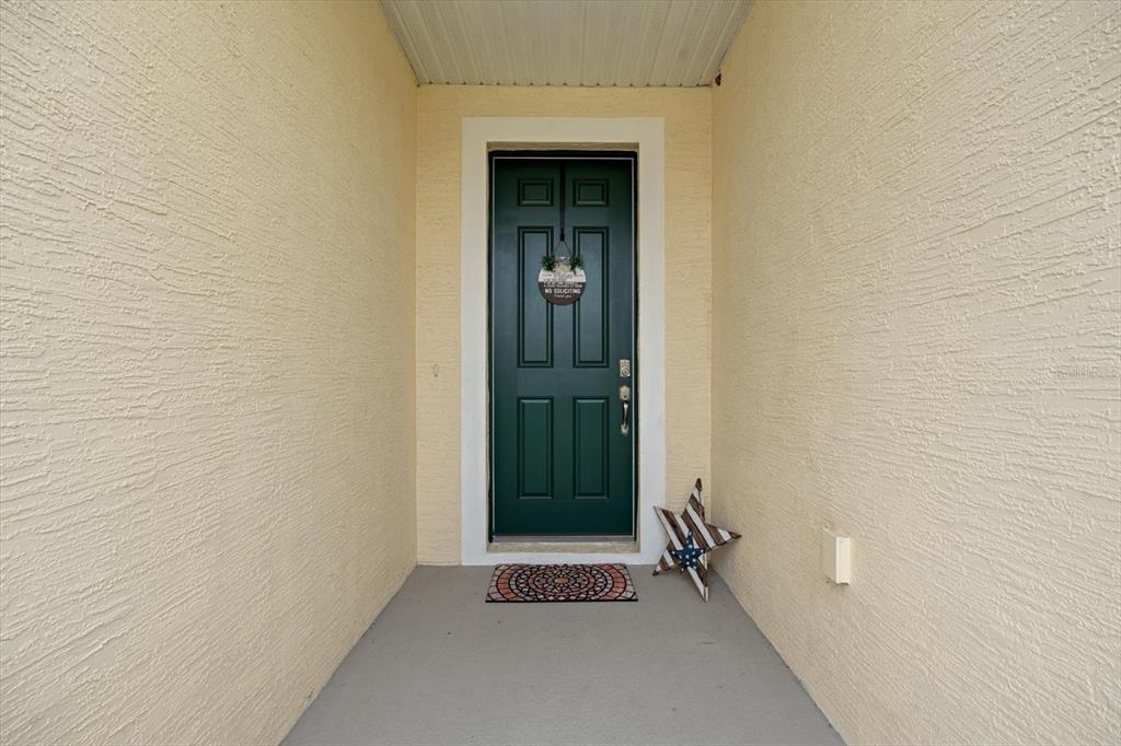 A dark green front door with a wreath sits at the end of a porch — 33 RIDGE ROAD, PALM COAST, FL