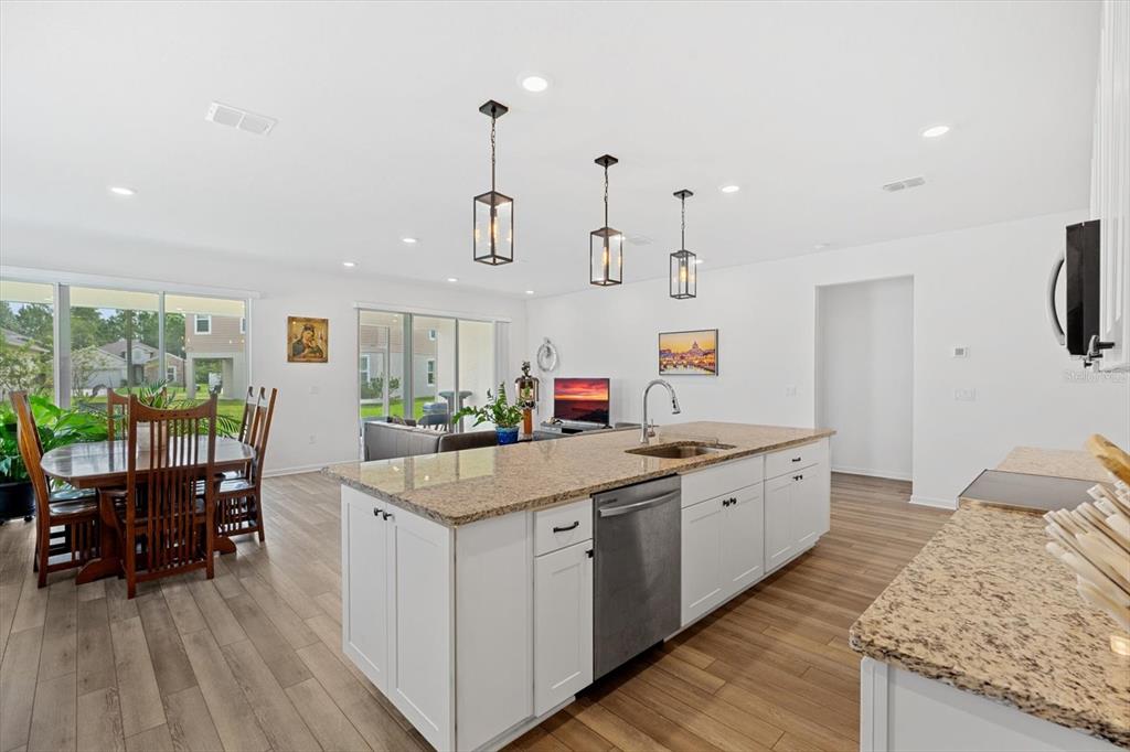 A kitchen with white cabinets, granite countertops, and a dining area in an open floor plan — 33 RIDGE ROAD, PALM COAST, FL