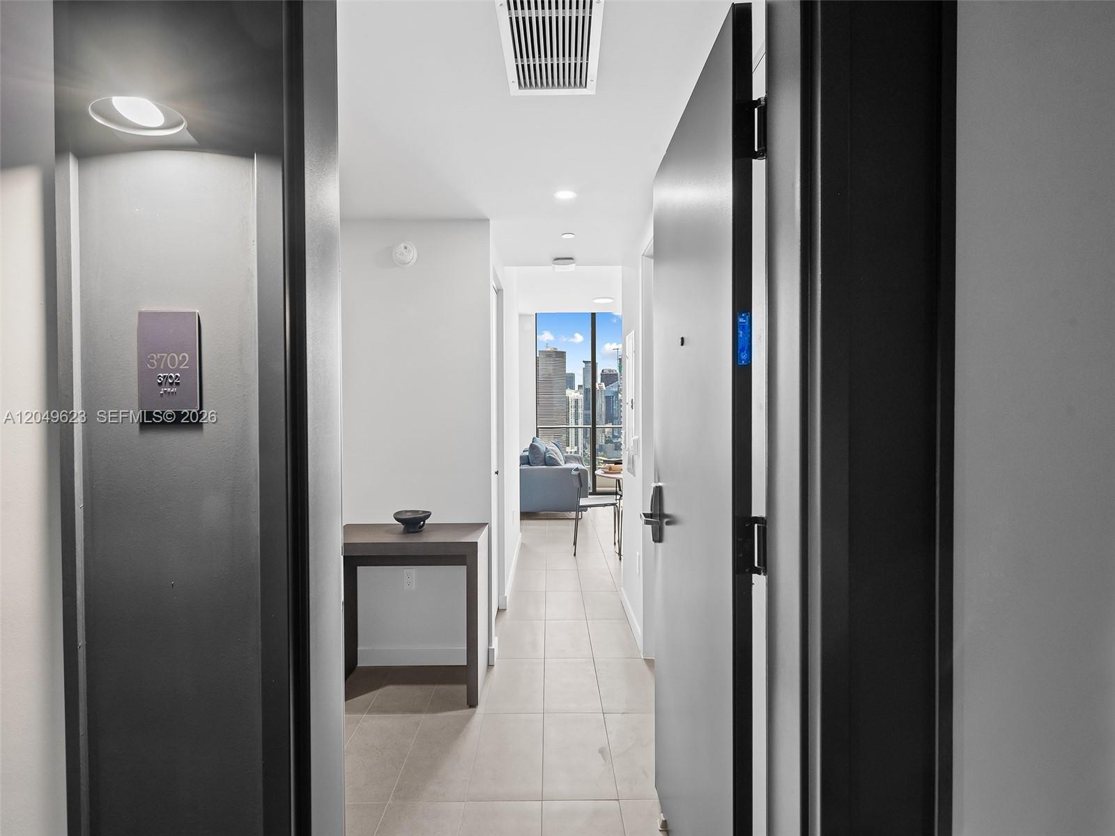 A view through an open doorway into a modern apartment hallway with city skyline views — 121 NE 5th St # 3703, Miami FL 33132, MIAMI, FL
