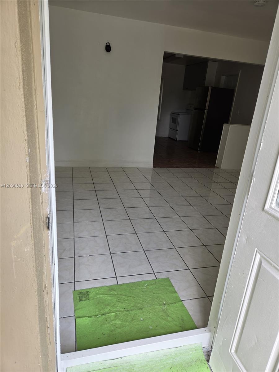 A view through a doorway shows a tiled room leading into a kitchen area — 5605 Taylor St # 1, Hollywood FL 33021, HOLLYWOOD, FL