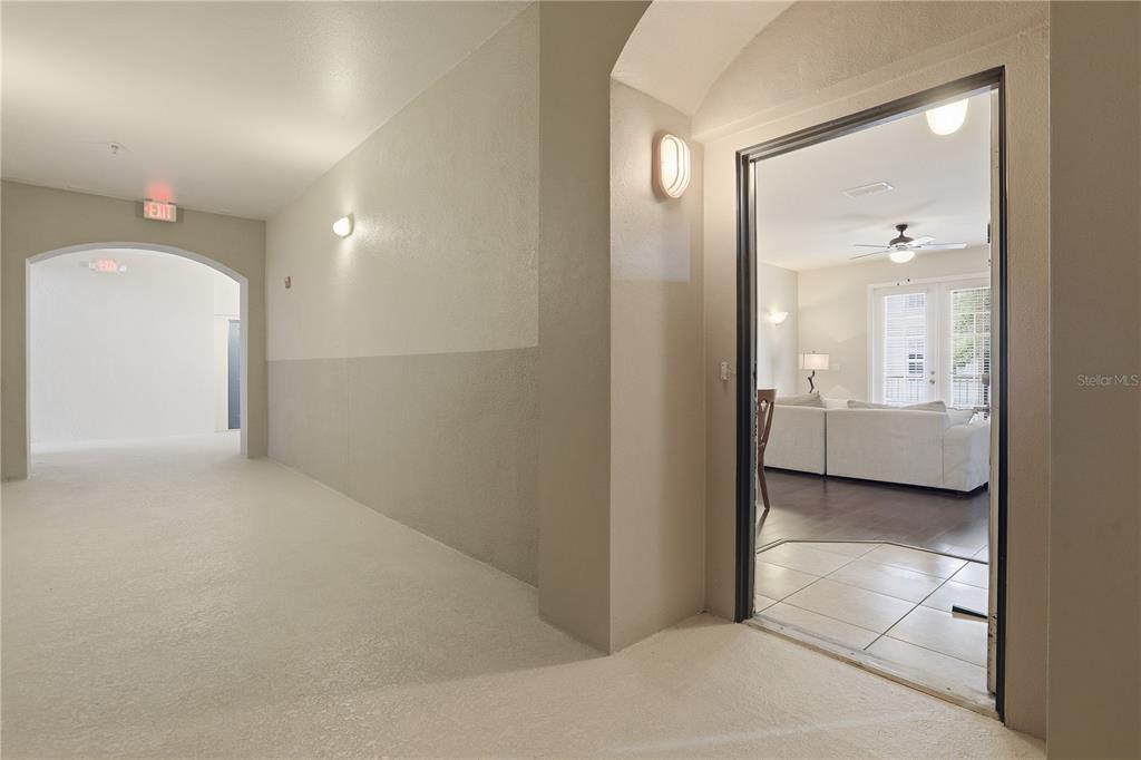 A view from a carpeted hallway looking into a living room with tile flooring — 3001 LAUREL RUN LANE UNIT 204, KISSIMMEE, FL