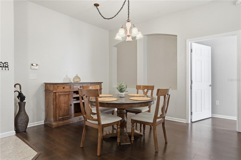 A dining room features a round wooden table, four chairs, a sideboard, and a chandelier — 3001 LAUREL RUN LANE UNIT 204, KISSIMMEE, FL