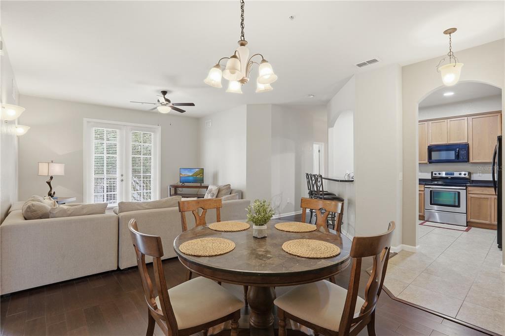A dining area with a round table sits in front of an open-concept living room — 3001 LAUREL RUN LANE UNIT 204, KISSIMMEE, FL