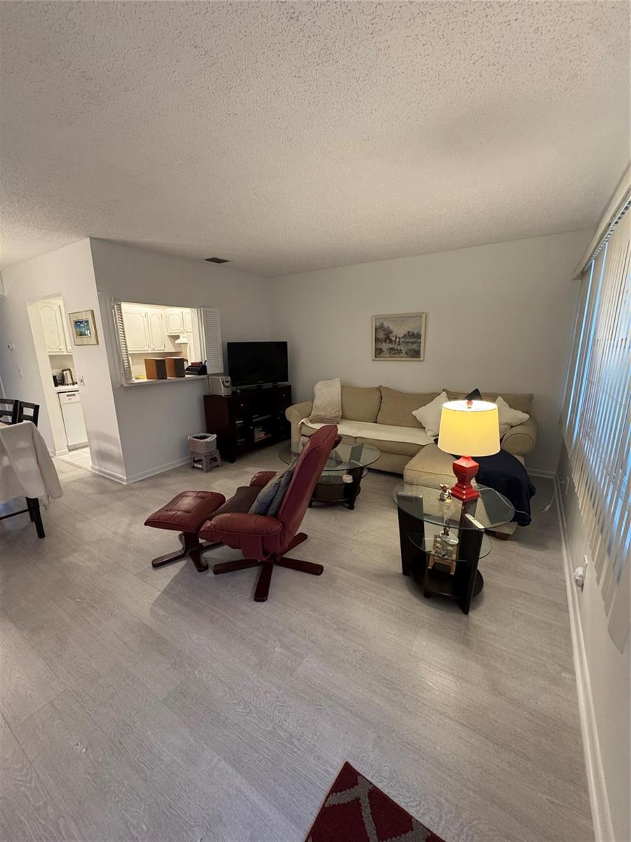 A living room features light wood-look flooring, a beige sectional, and a red leather recliner — 283 Ventnor # 283, Deerfield Beach FL 33442, DEERFIELD BEACH, FL