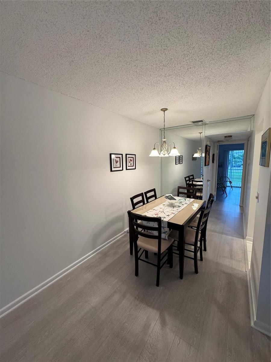 A dining area features light wood-look flooring, a mirrored wall, and a four-person table — 283 Ventnor # 283, Deerfield Beach FL 33442, DEERFIELD BEACH, FL