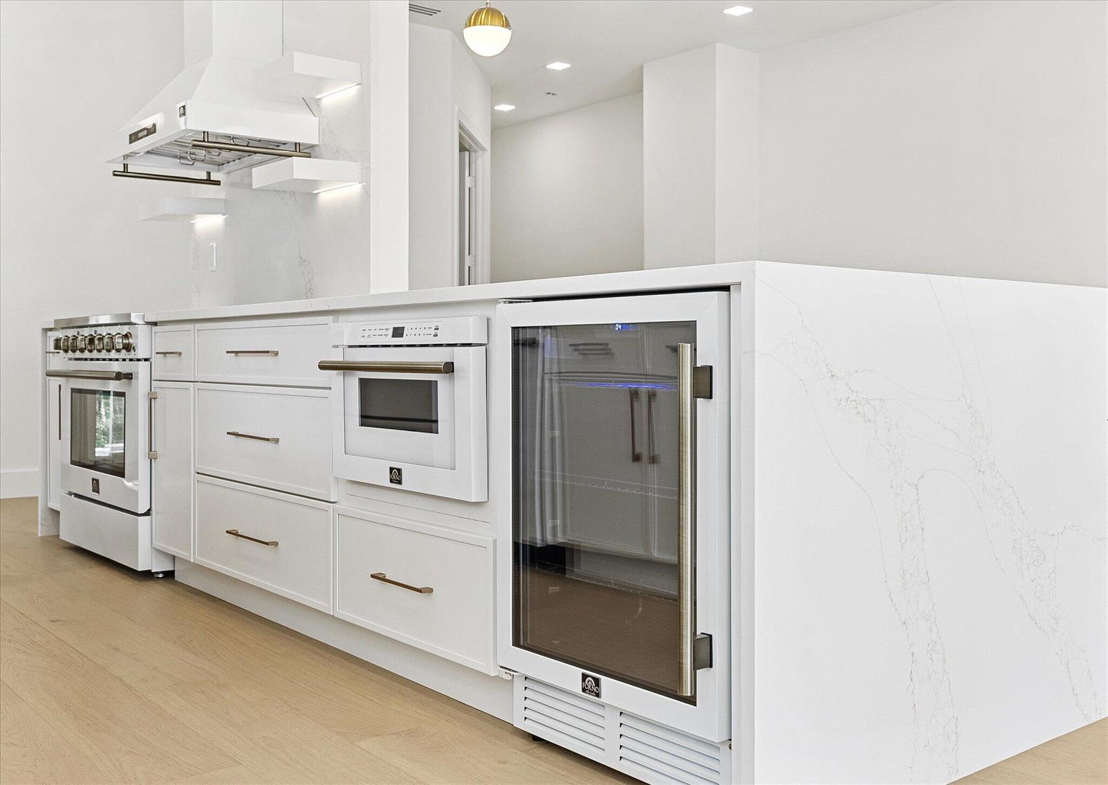 A modern white kitchen island features a built-in oven, wine cooler, and marble countertop — 4789 Valencia Drive, Delray Beach FL 33445, DELRAY BEACH, FL