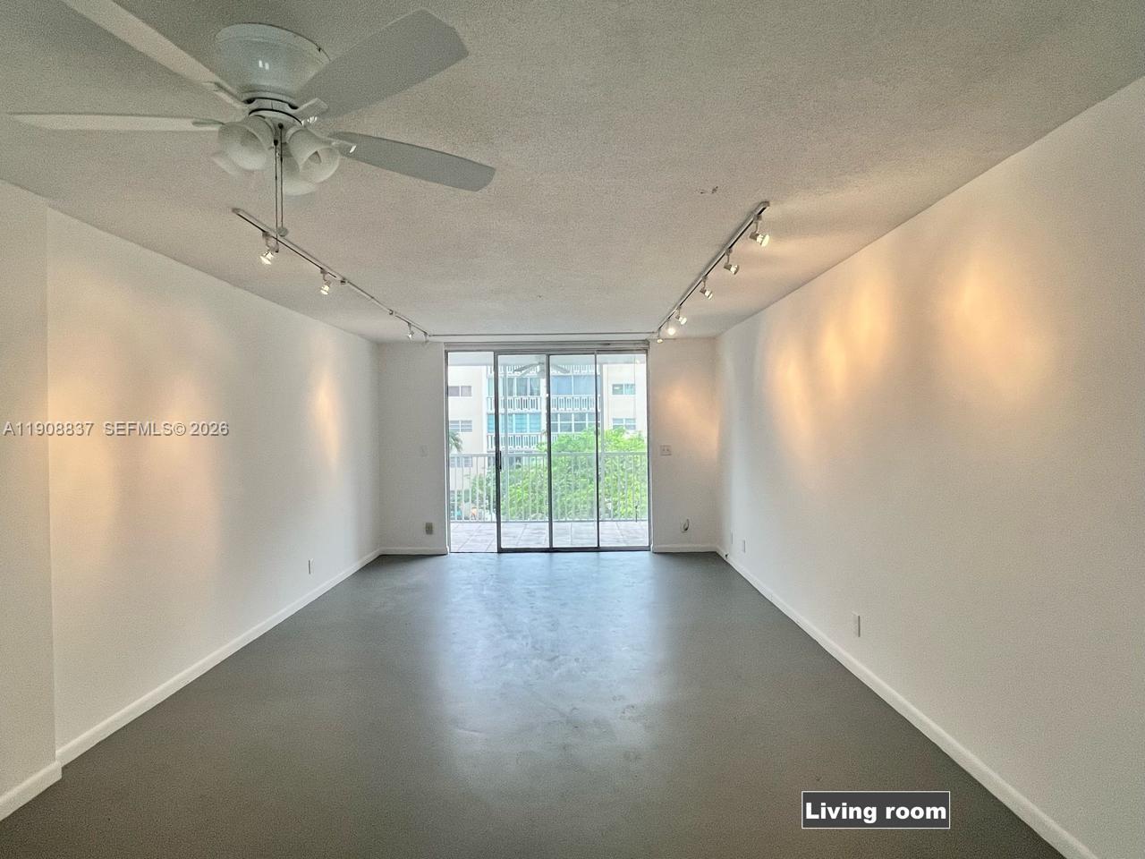 An empty living room features gray flooring, white walls, track lighting, and a ceiling fan — 619 NE 14th Ave # 304, Hallandale Beach FL 33009, HALLANDALE BEACH, FL