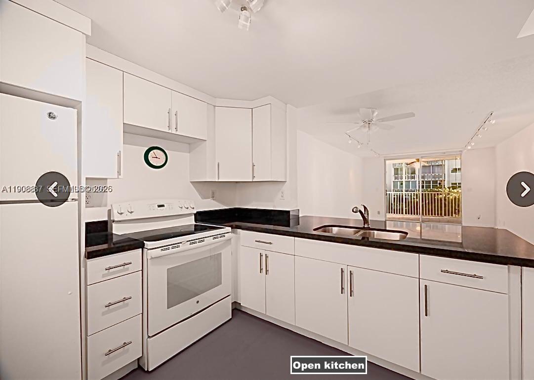 This kitchen features white cabinets, black countertops, and a white stove — 619 NE 14th Ave # 304, Hallandale Beach FL 33009, HALLANDALE BEACH, FL