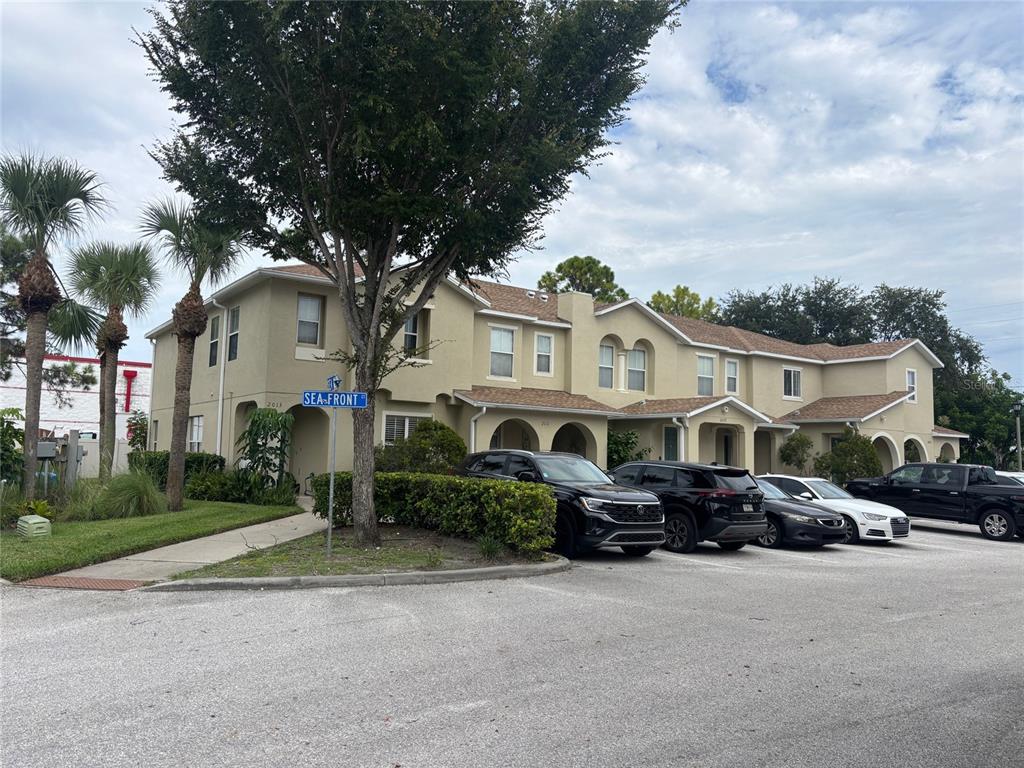 A two-story tan apartment building with a parking lot and palm trees in front — 2013 SEA FRONT COURT, CLEARWATER, FL