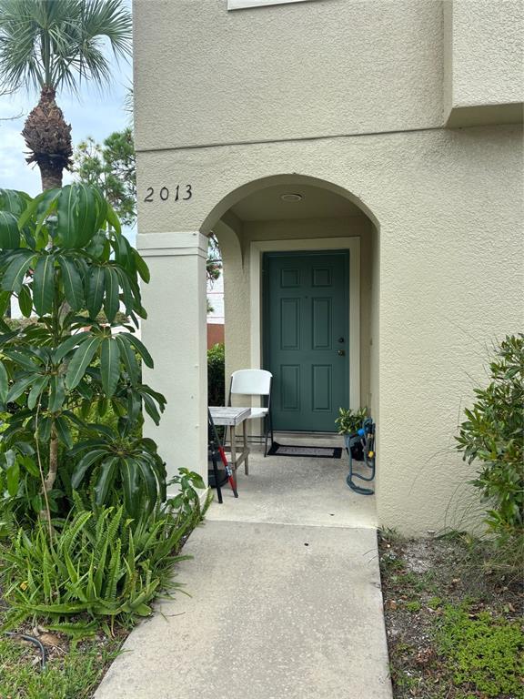A concrete walkway leads to the arched entryway of a building with a green door — 2013 SEA FRONT COURT, CLEARWATER, FL