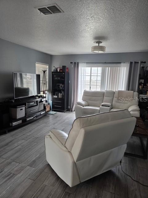 A living room features gray walls, wood-look tile flooring, a television console, and white recliners — 2013 SEA FRONT COURT, CLEARWATER, FL