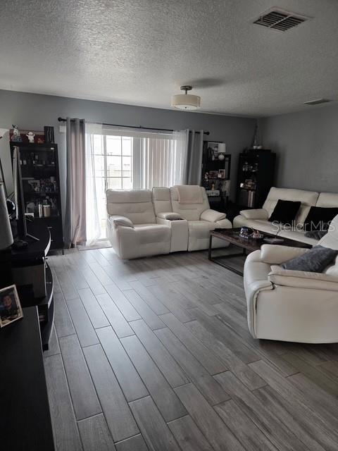 A living room features gray wood-look tile flooring, white reclining furniture, and a sliding glass door — 2013 SEA FRONT COURT, CLEARWATER, FL