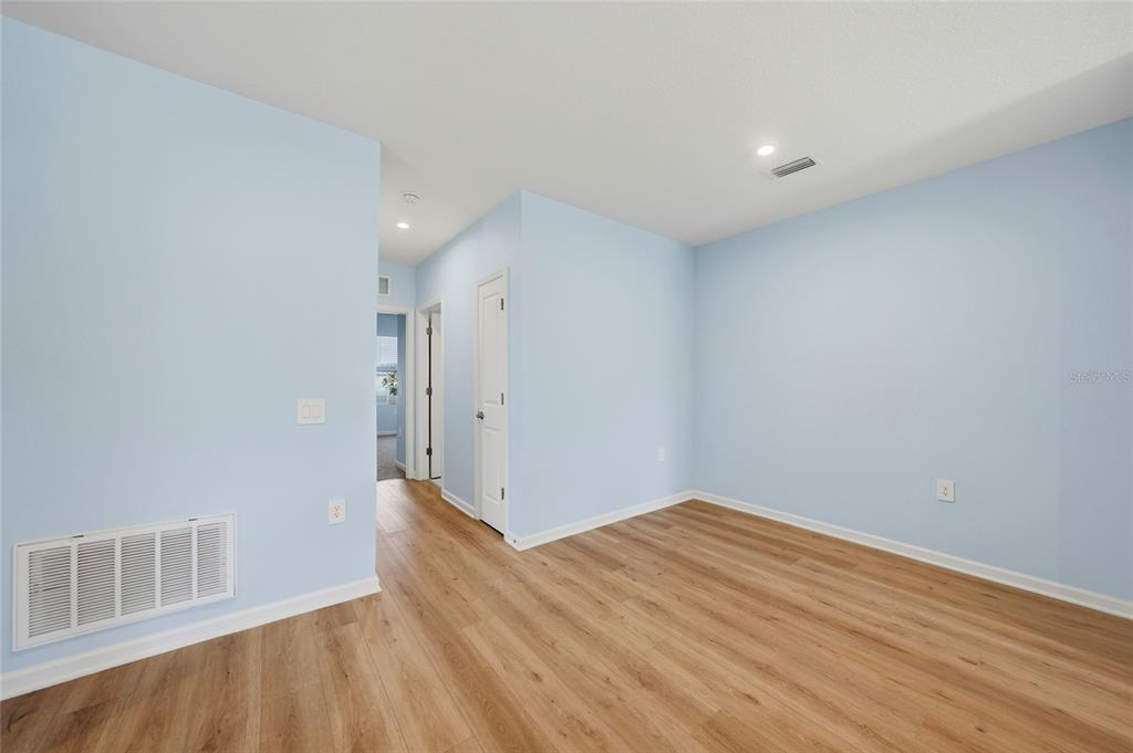 An empty room with light blue walls, wood-look flooring, and a white door — 1988 W PALMS DRIVE, PORT CHARLOTTE, FL