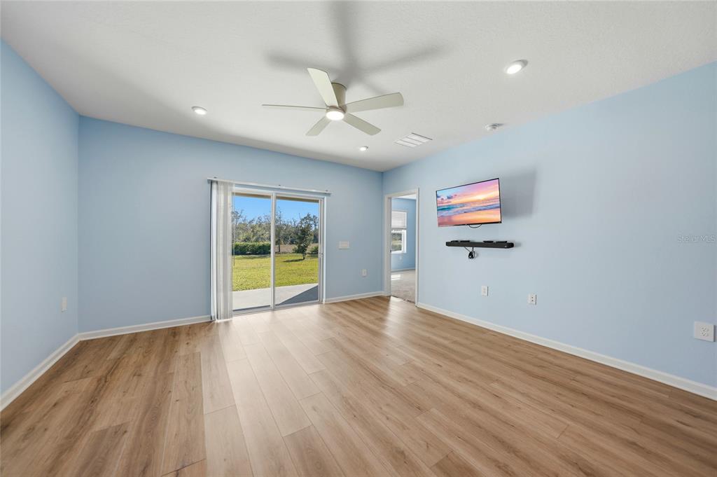 A light blue room features wood-look flooring, a ceiling fan, and a sliding glass door — 1988 W PALMS DRIVE, PORT CHARLOTTE, FL