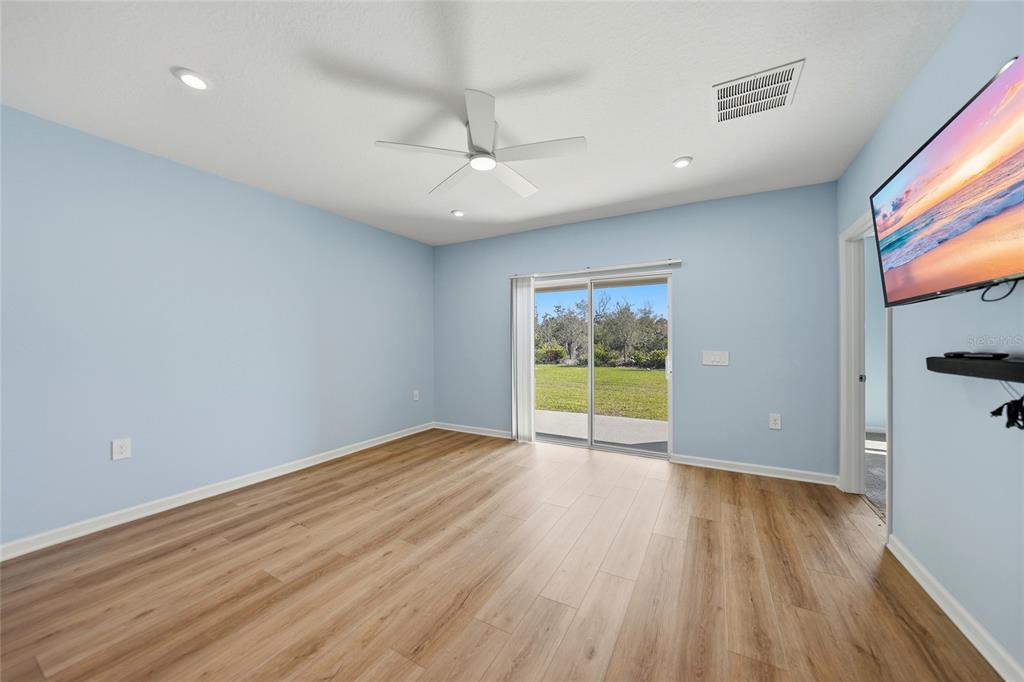 A light blue room with wood-look flooring, a ceiling fan, and sliding glass patio doors — 1988 W PALMS DRIVE, PORT CHARLOTTE, FL
