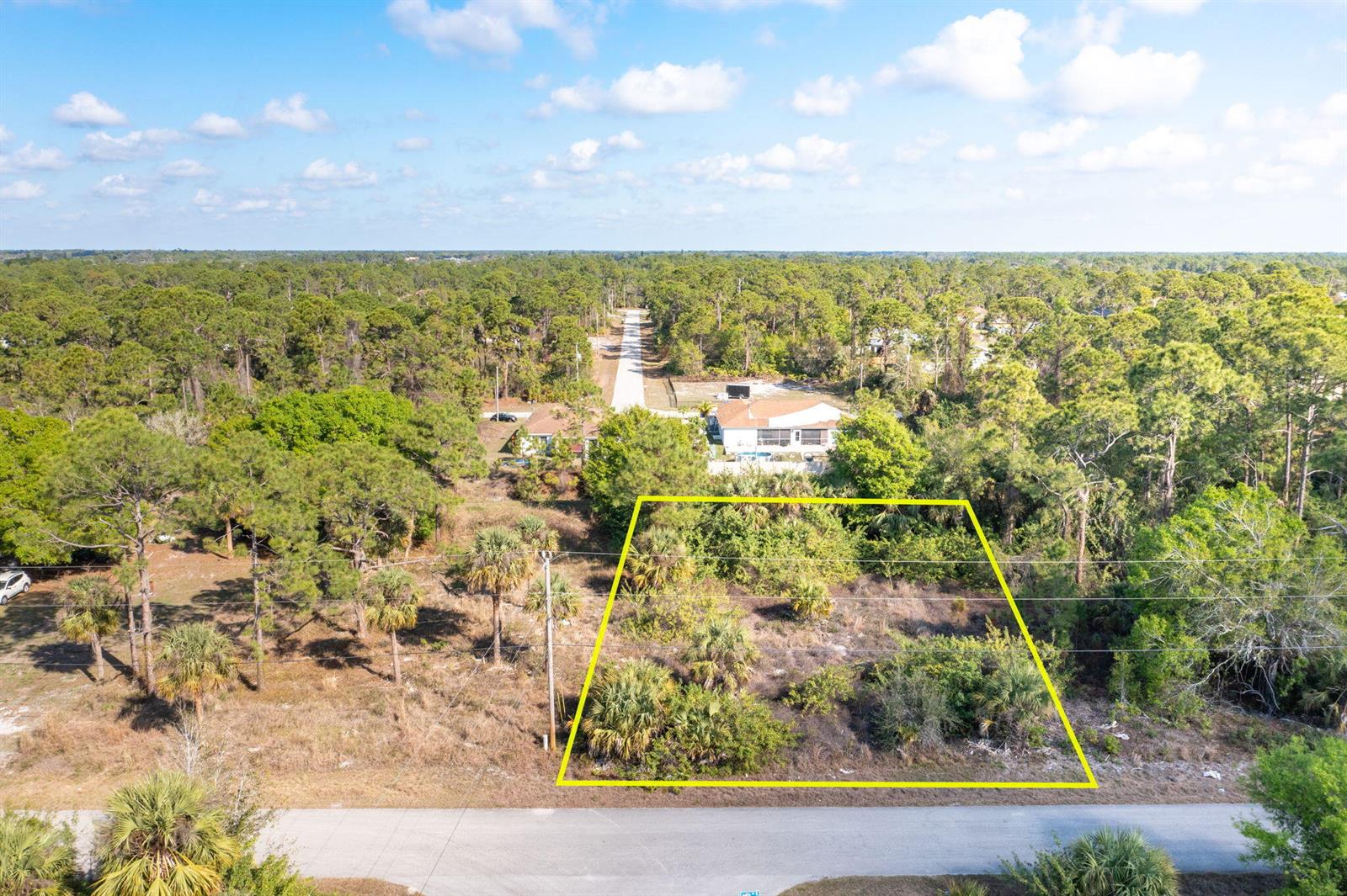 An aerial view shows a vacant, rectangular lot outlined in yellow along a paved road — 773 Cadis Street E, Lehigh Acres FL 33974, LEHIGH ACRES, FL