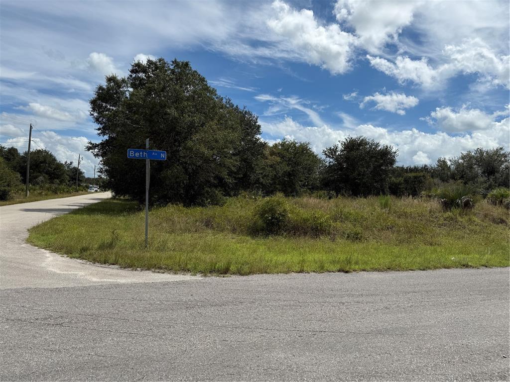 A street sign for Beth Av N stands at the corner of a grassy vacant lot — 2513 72ND STREET W, LEHIGH ACRES, FL