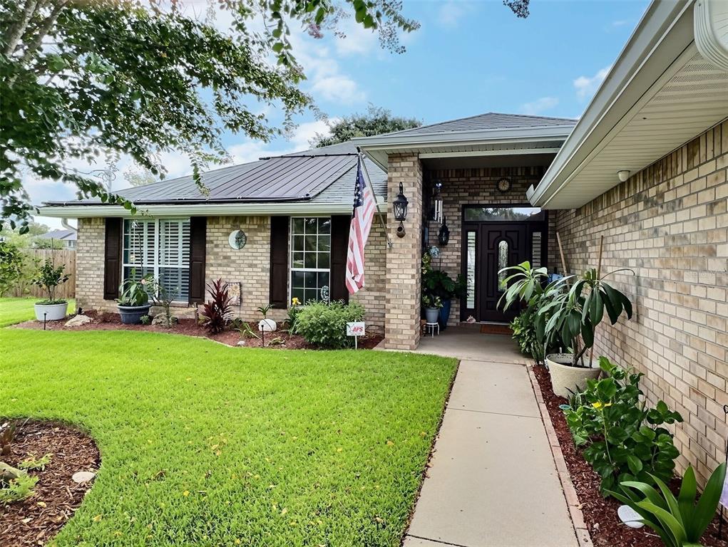A brick house with a metal roof, front porch, and a landscaped front yard — 28 FIELDING LANE, PALM COAST, FL