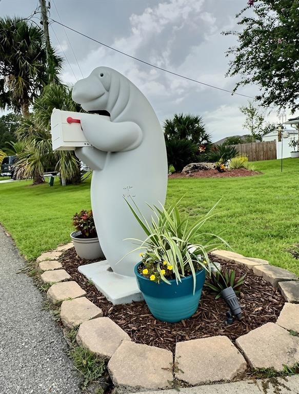 A manatee-shaped mailbox stands in a landscaped garden bed with a potted plant — 28 FIELDING LANE, PALM COAST, FL