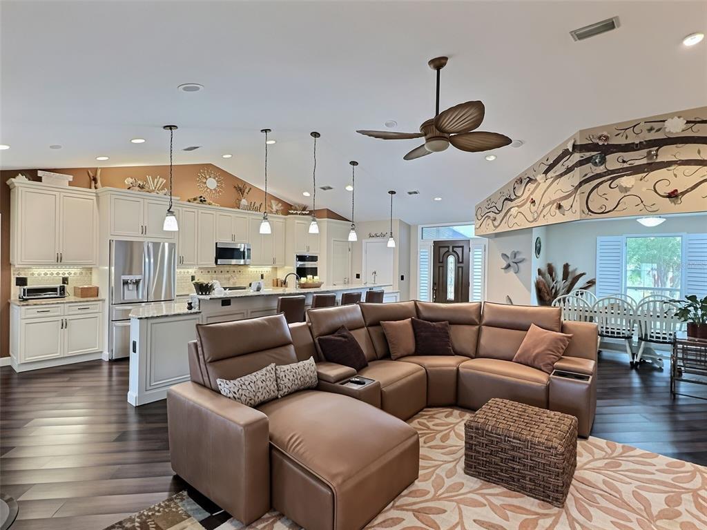 An open-concept kitchen and living area features a brown leather sectional, white cabinetry, and hardwood floors — 28 FIELDING LANE, PALM COAST, FL