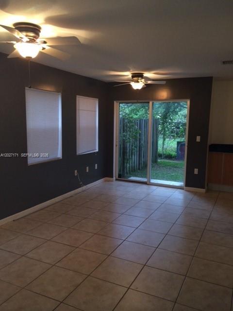 A living room with tile flooring, two ceiling fans, dark walls, and a sliding glass door — 1702 N 28th Ave # 1, Hollywood FL 33020, HOLLYWOOD, FL