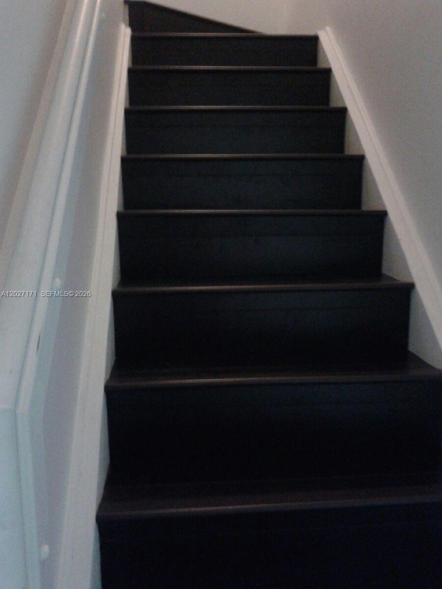 A straight staircase with dark-painted wooden steps and white trim — 1702 N 28th Ave # 1, Hollywood FL 33020, HOLLYWOOD, FL
