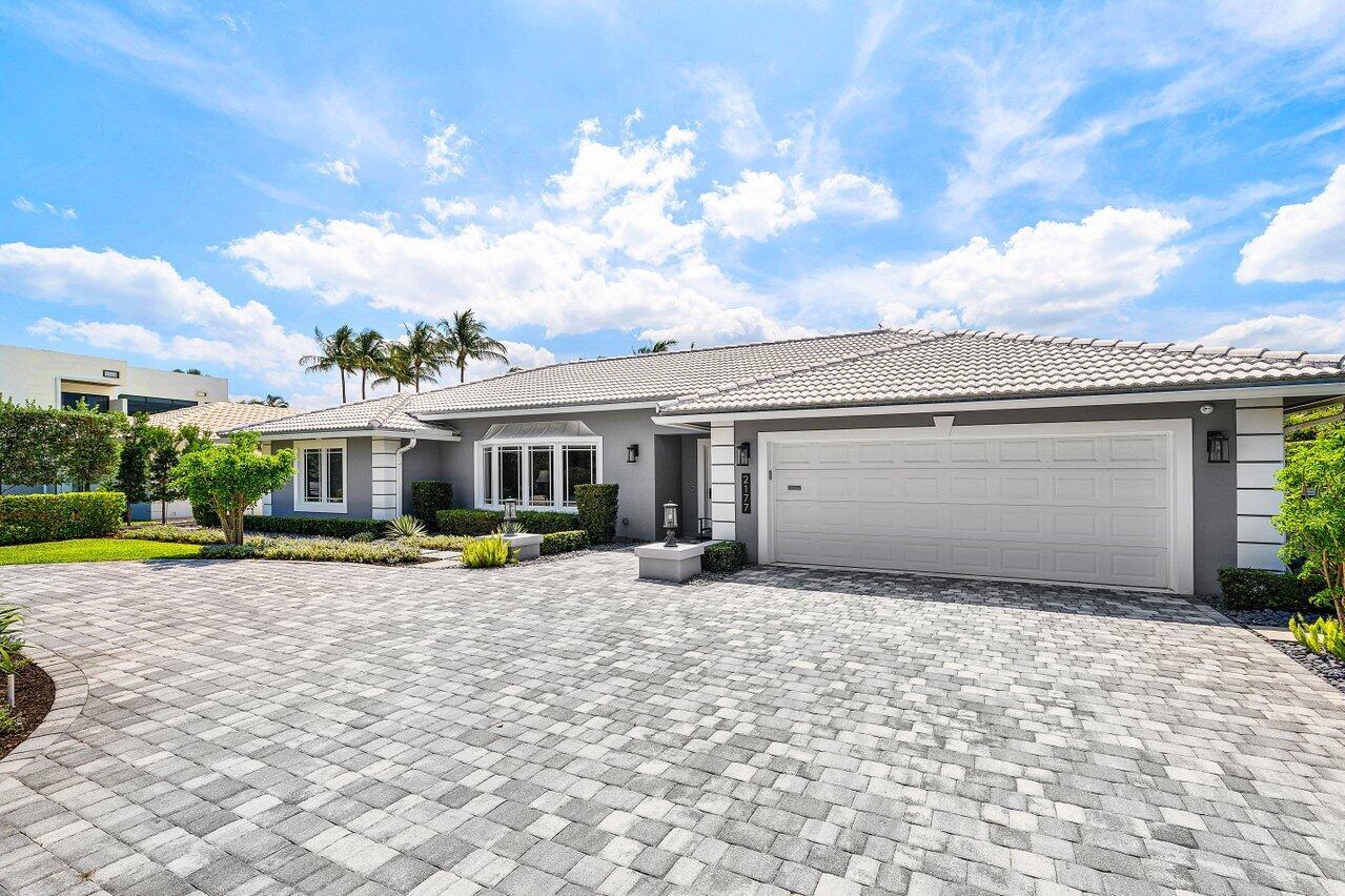 A gray single-story house features a white garage door and a paved stone driveway — 2177 Areca Palm Road, Boca Raton FL 33432, BOCA RATON, FL