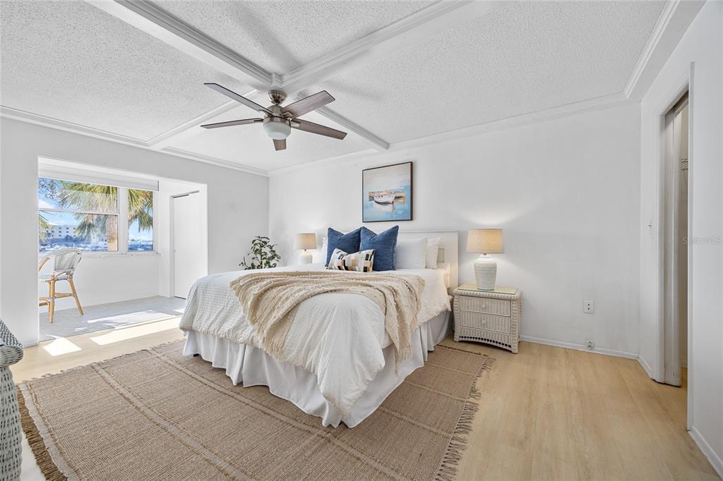 A bedroom features a king bed, a ceiling fan, a woven rug, and a balcony — 4775 COVE CIRCLE UNIT 203, ST PETERSBURG, FL