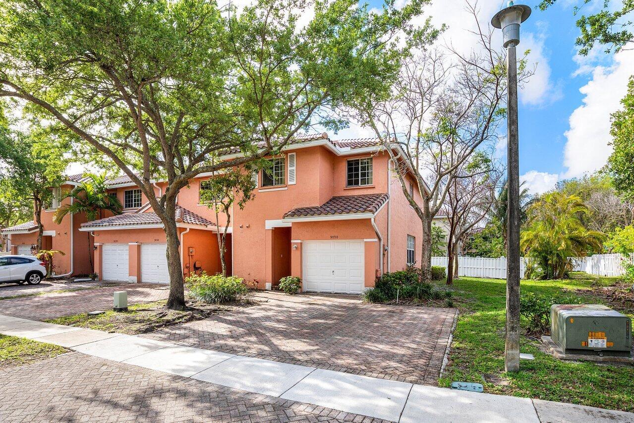 A two-story peach-colored townhouse with a brick driveway and a white garage door — 9090 NW 40th Place, Sunrise FL 33351, SUNRISE, FL