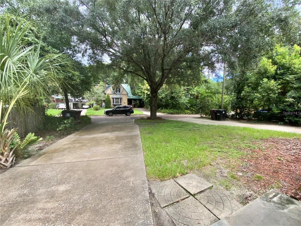 A green single-story duplex with two front doors and concrete driveways under large trees — 1022 DELANEY PARK DRIVE UNIT 1020, ORLANDO, FL