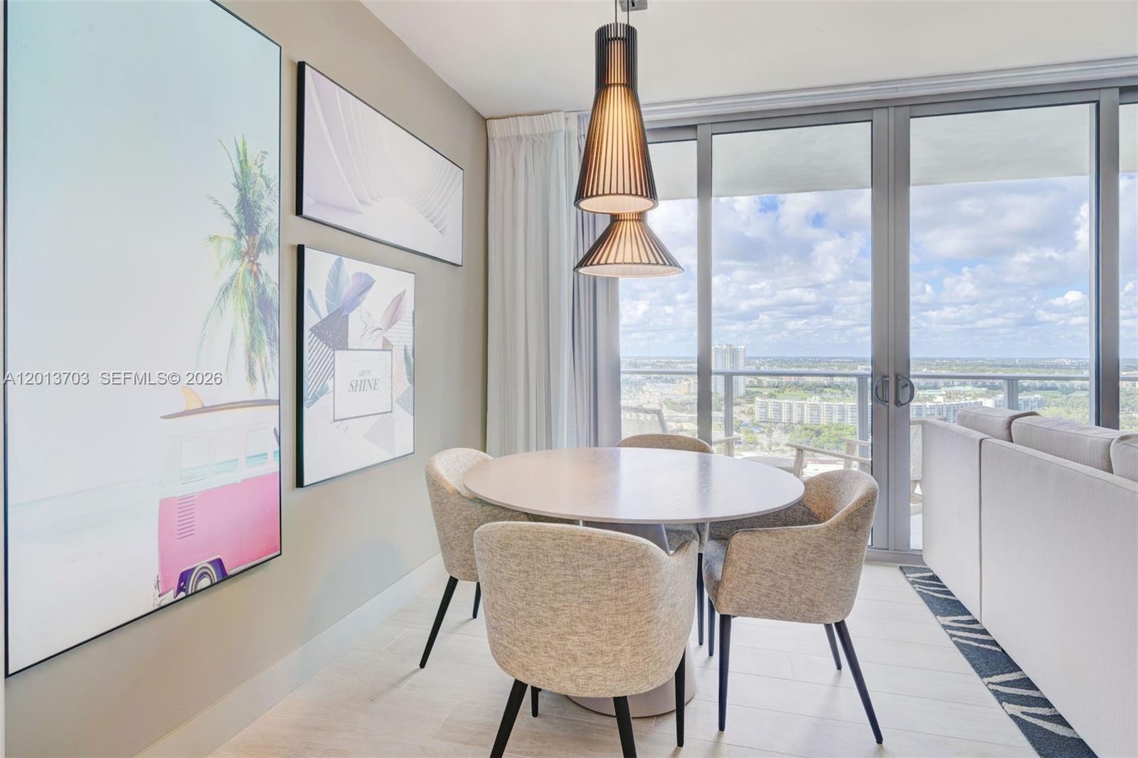 A dining area features a round table, four upholstered chairs, modern pendant lighting, and wall art — 4010 S Ocean Dr # R2106, Hollywood FL 33019, HOLLYWOOD, FL