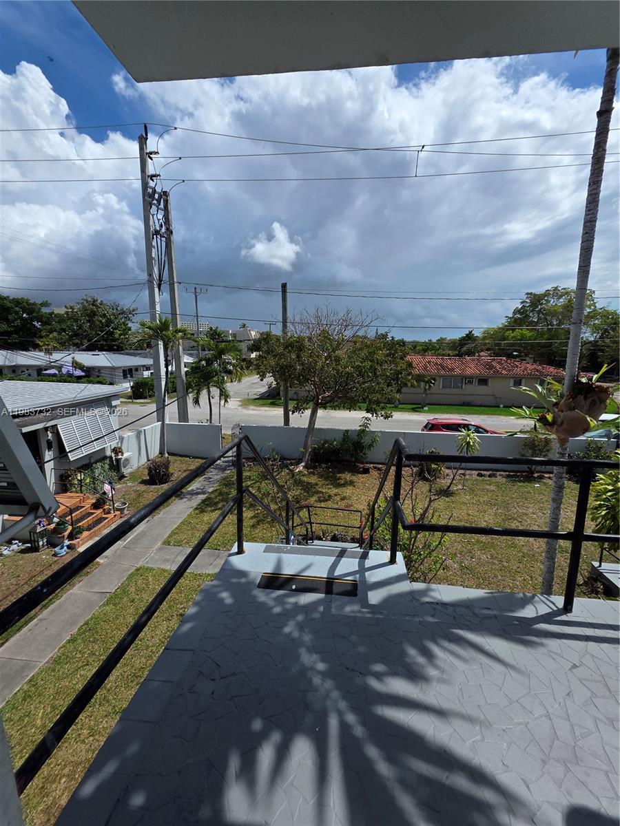 An elevated view from a balcony overlooking a residential yard, street, and neighboring houses — 71 Esplanade Dr # D, Miami Springs FL 33166, MIAMI SPRINGS, FL