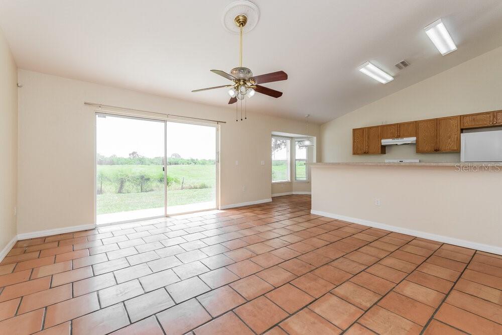 An open-concept living area features tile flooring, a ceiling fan, and a kitchen pass-through window — 1001 GARY DRIVE, ST CLOUD, FL